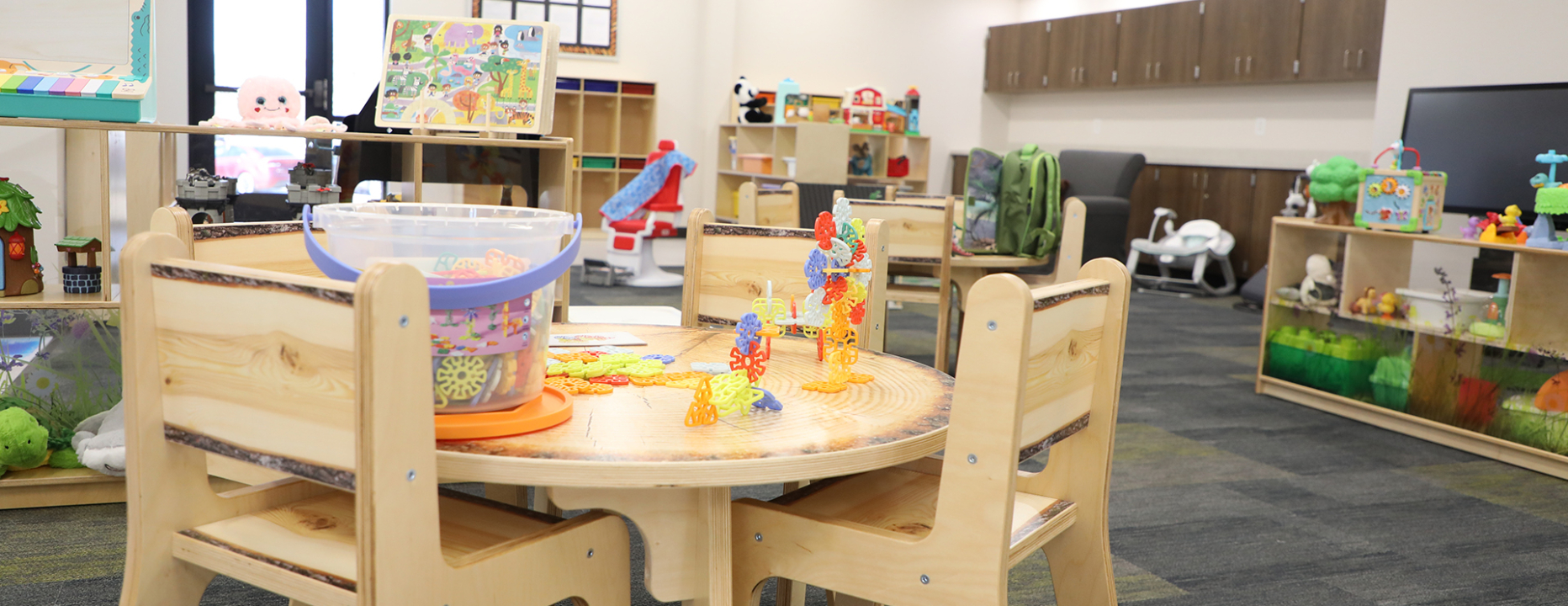 Child care specialist header photo inside of daycare center wooden table with kids toys on top